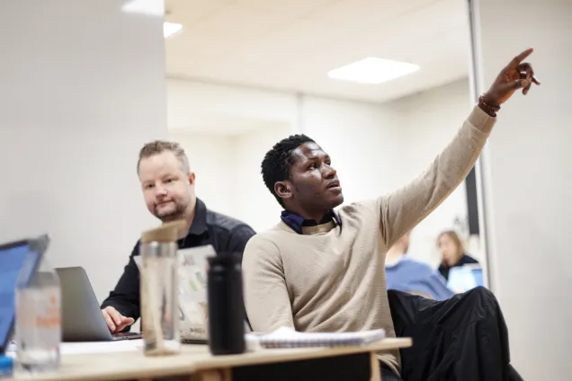 Two students at their desk in a seminar. Photo.